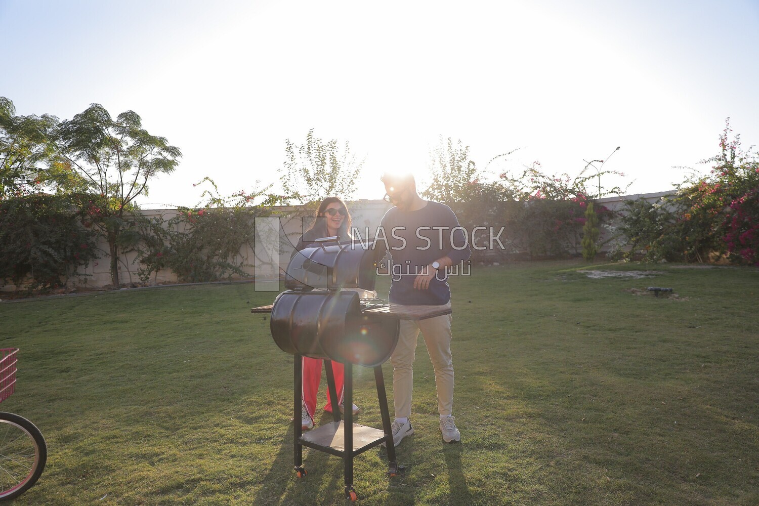 a couple preparing food on a barbecue grill