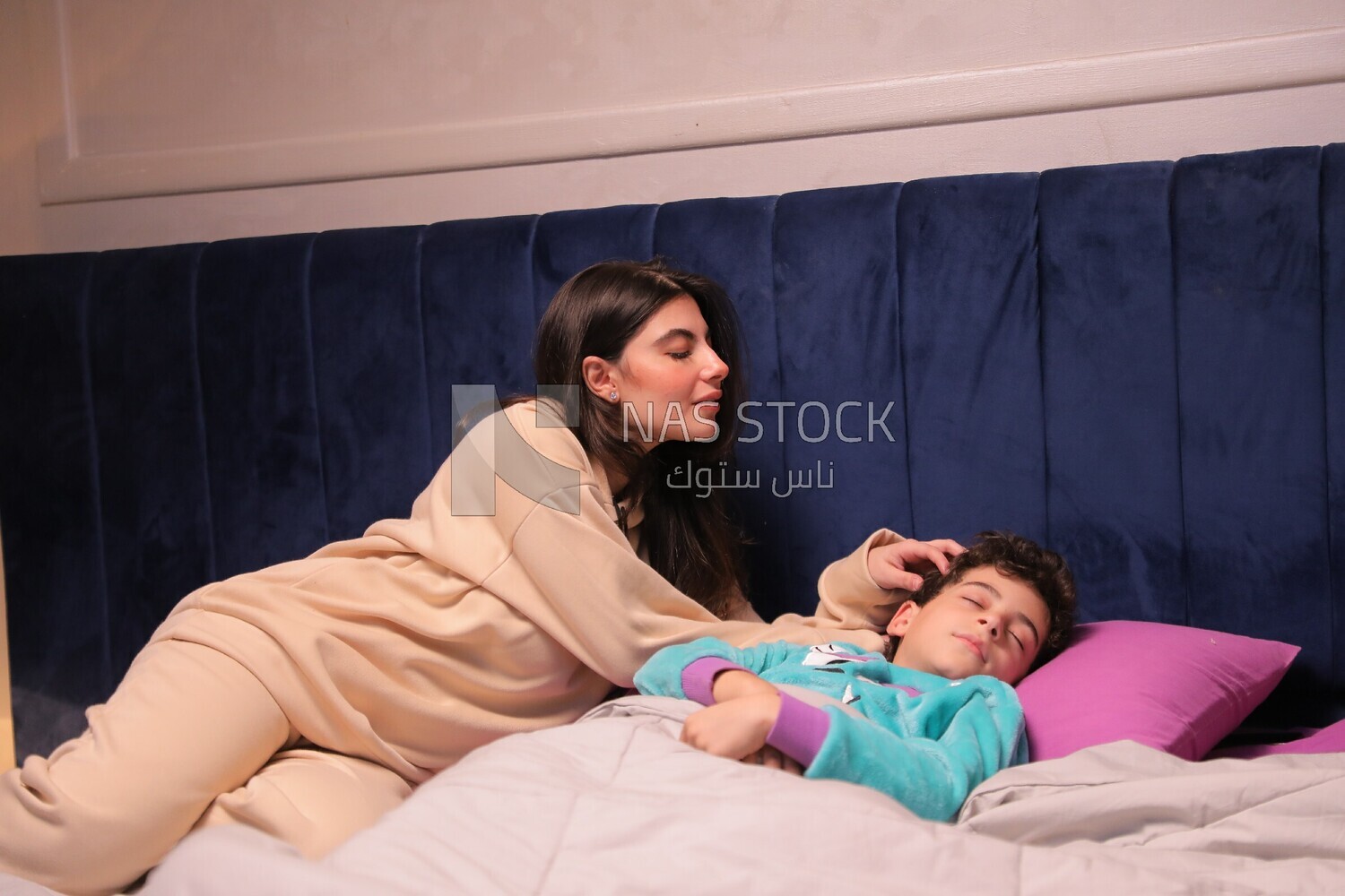 a mother sitting on the bed during his boy&#39;s sleep