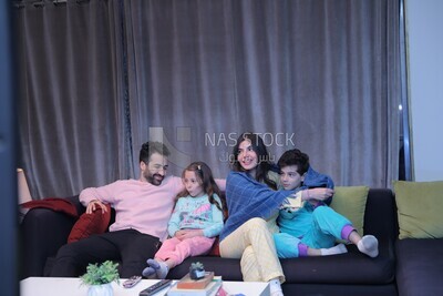 a family of four sitting on the sofa laughing