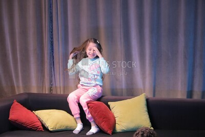 a girl sitting on the sofa in front of the television