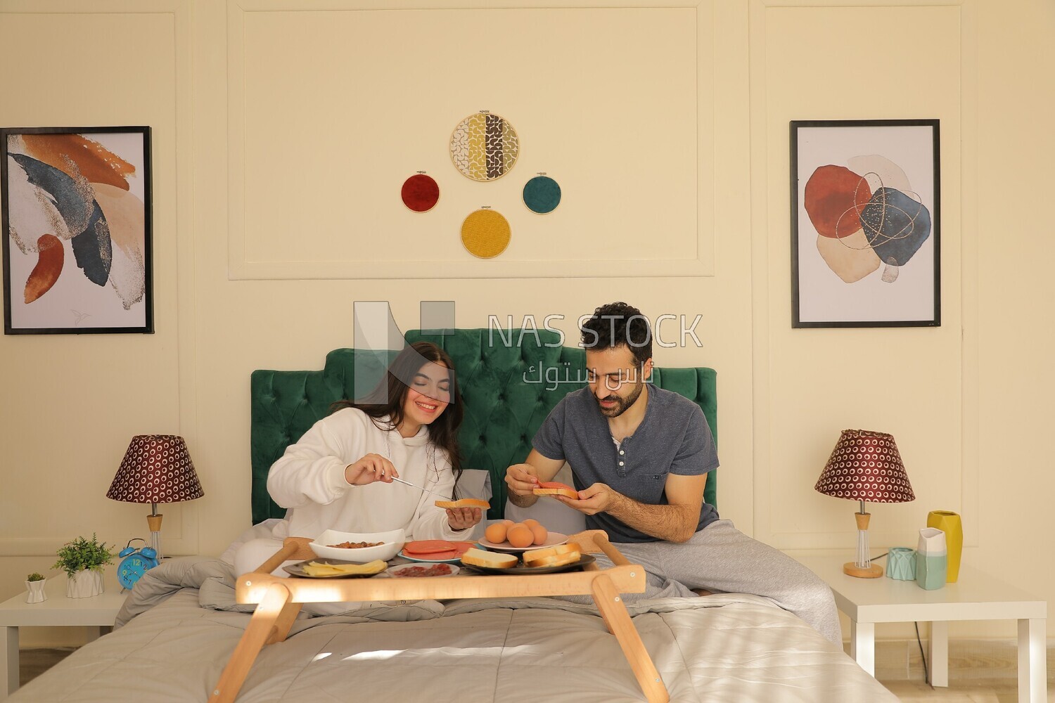 a man and a woman having breakfast on the bed