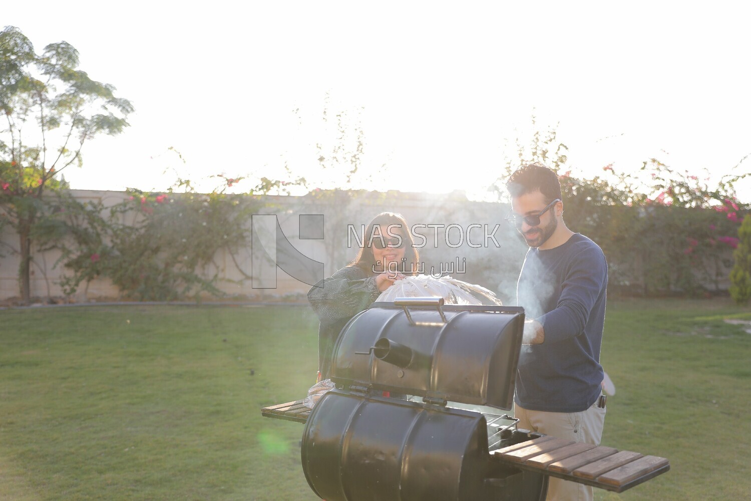 a couple preparing food on a barbecue grill