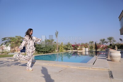 a woman standing in the garden beside a swimming pool
