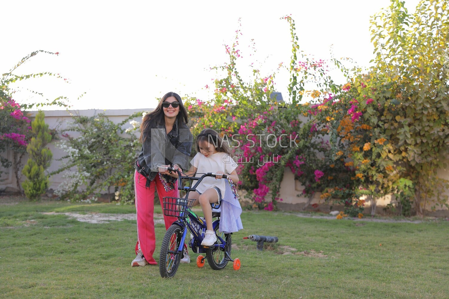 a woman helping her daughter ride a bike