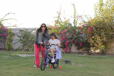 a woman helping her daughter ride a bike