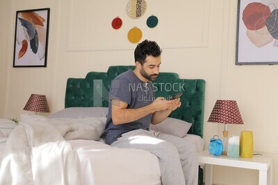 a man sitting in bed holding his mobile