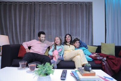 a family of four sitting on the sofa laughing