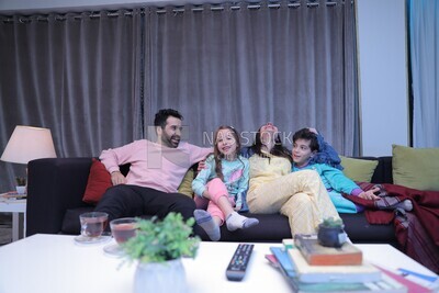 a family of four sitting on the sofa laughing
