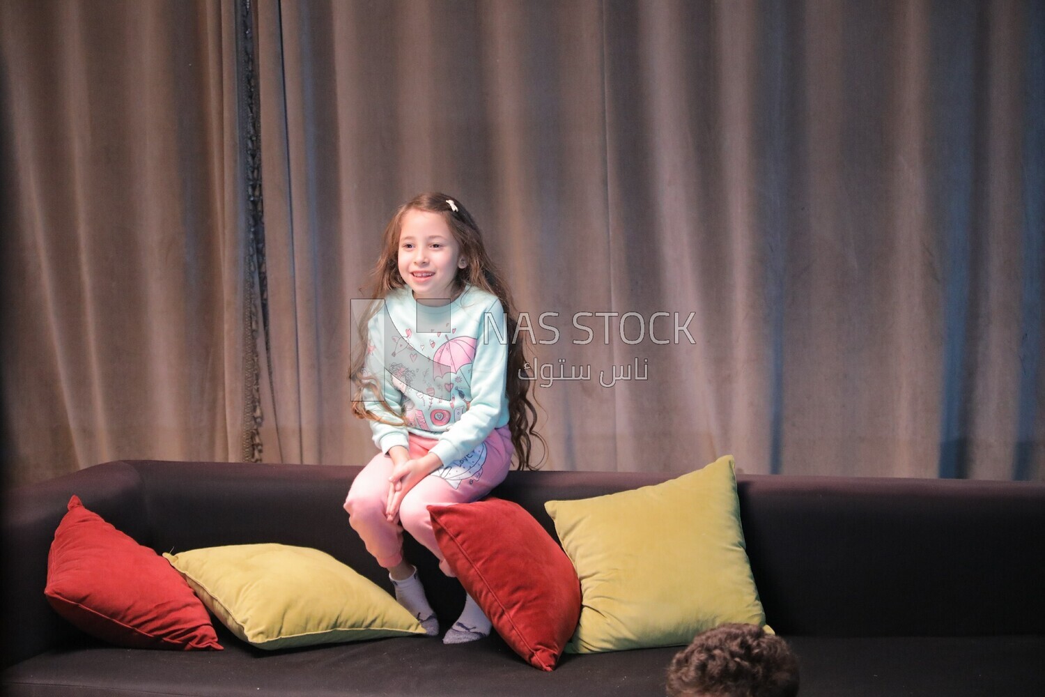 a girl sitting on the sofa in front of the television