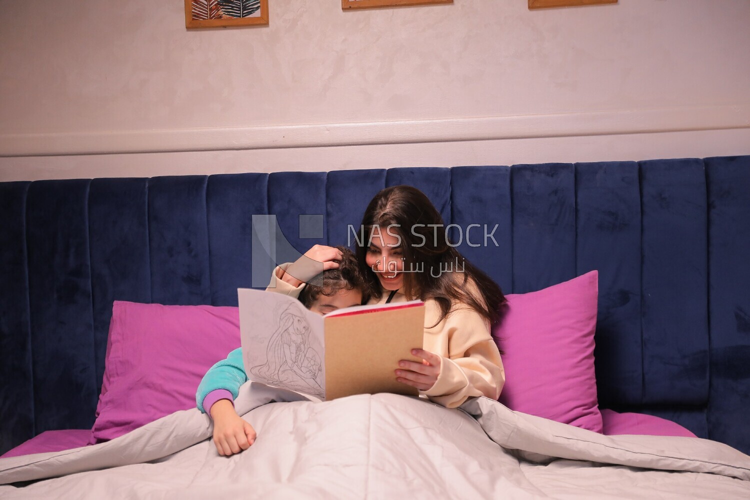 a woman reading a story to her son in bed