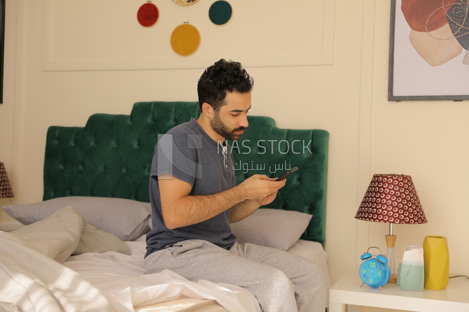 a man sitting in bed holding his mobile