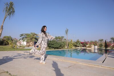a woman standing in the garden beside a swimming pool