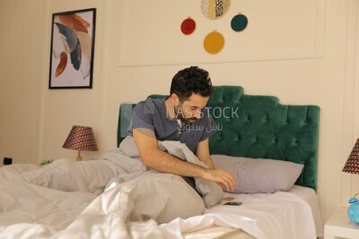 a man sitting in bed holding his mobile