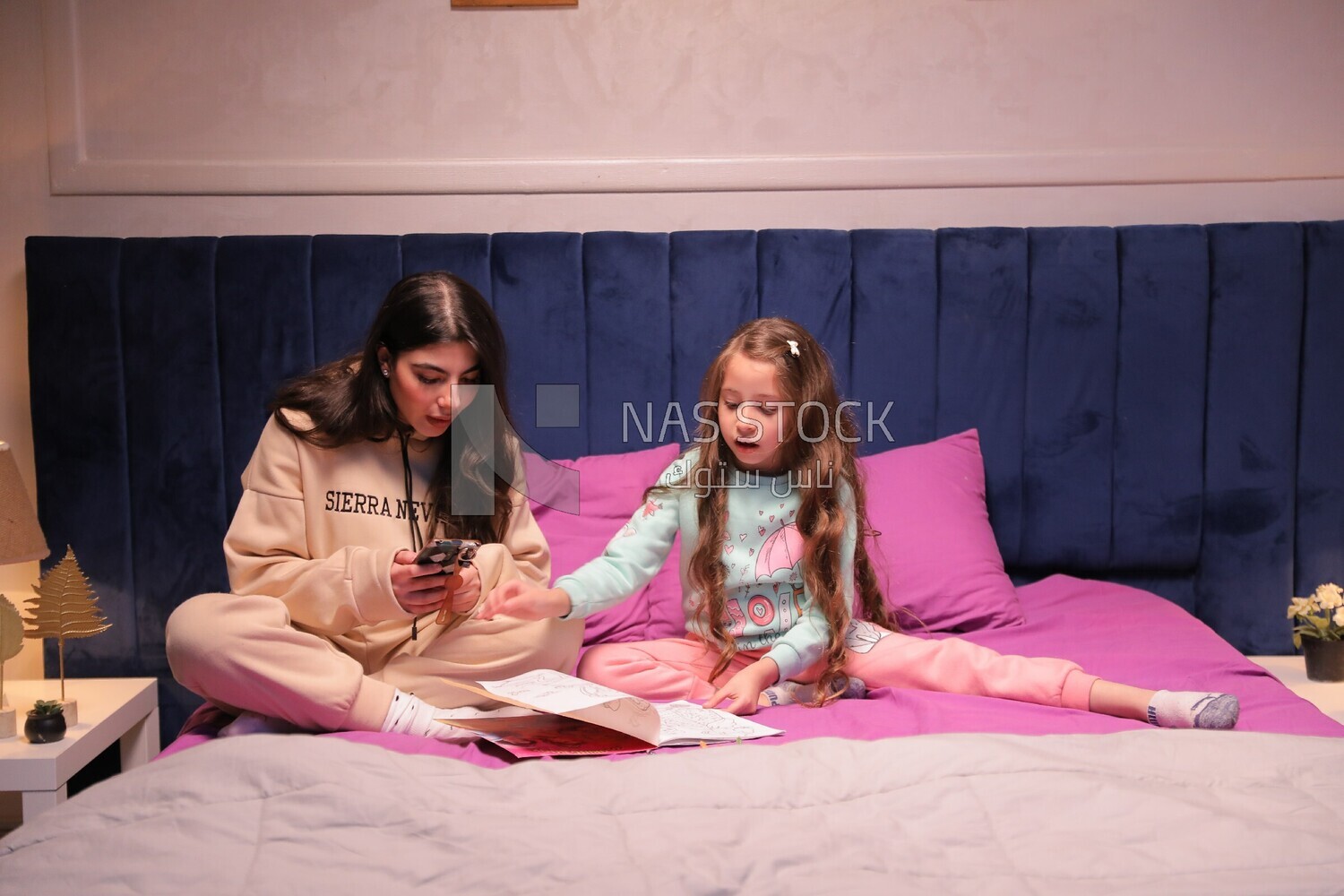 a mother with her daughter drawing together on the bed
