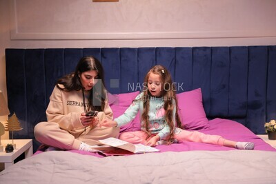 a mother with her daughter drawing together on the bed