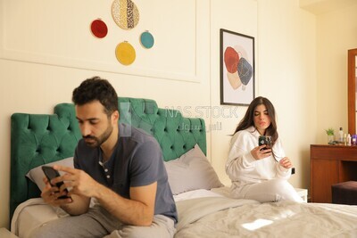 a man texting on the phone while her wife is beside him