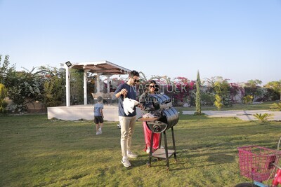 a couple preparing food on a barbecue grill