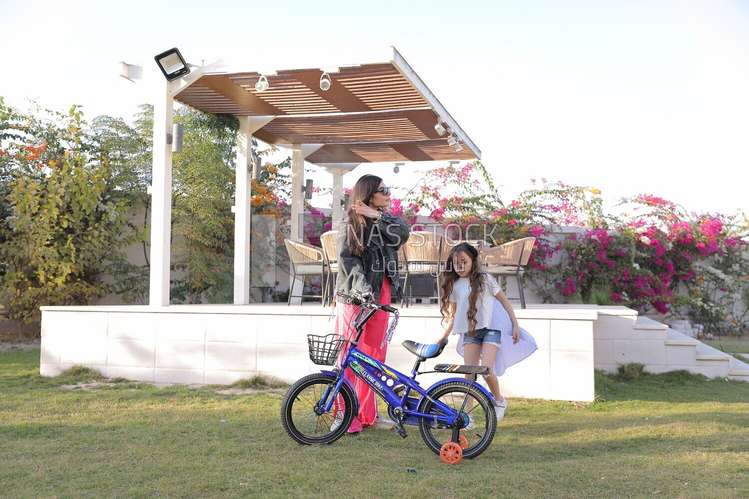 a woman helping her daughter ride a bike