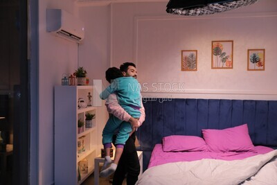 a father carrying his boy and putting him in bed