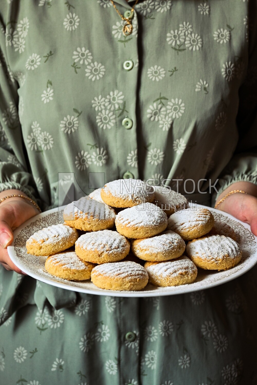 Hand holding a plate of egyptian eid cookies