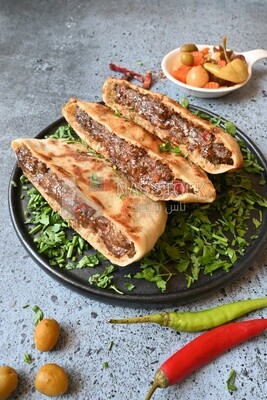 dish with hawawshi next to a spicy pepper