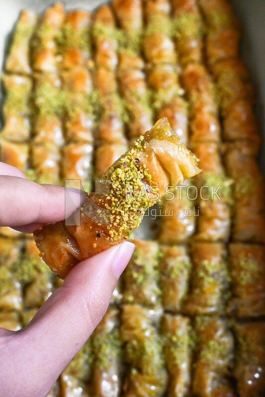 Hand holding a piece of egyptian sweet goulash with nuts on it