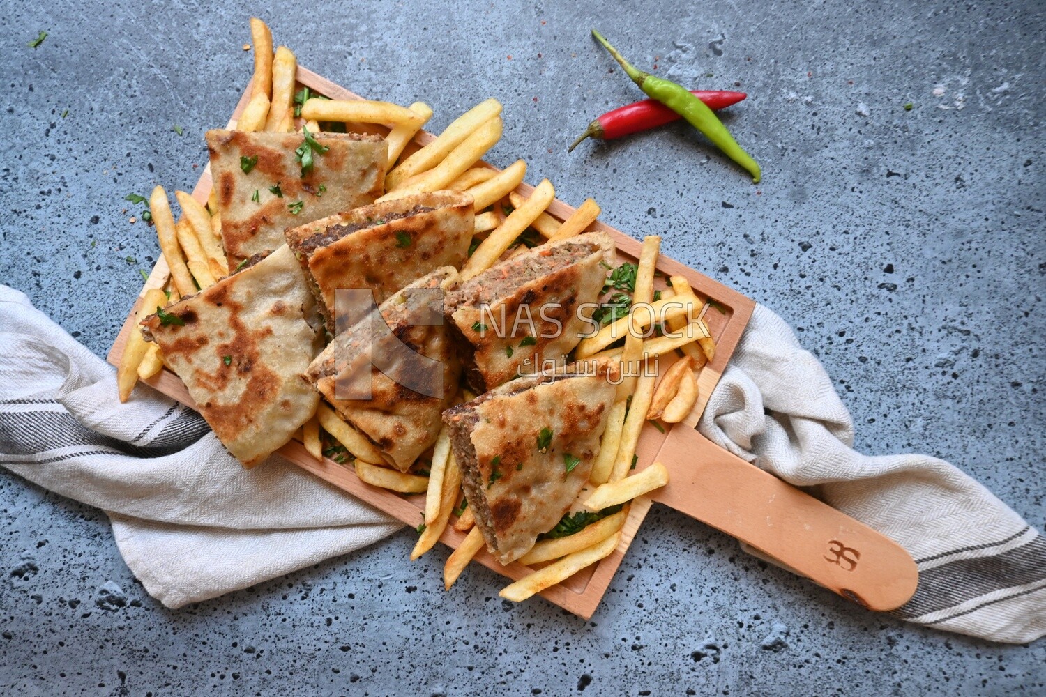 dish with hawawshi next to a spicy pepper and fries