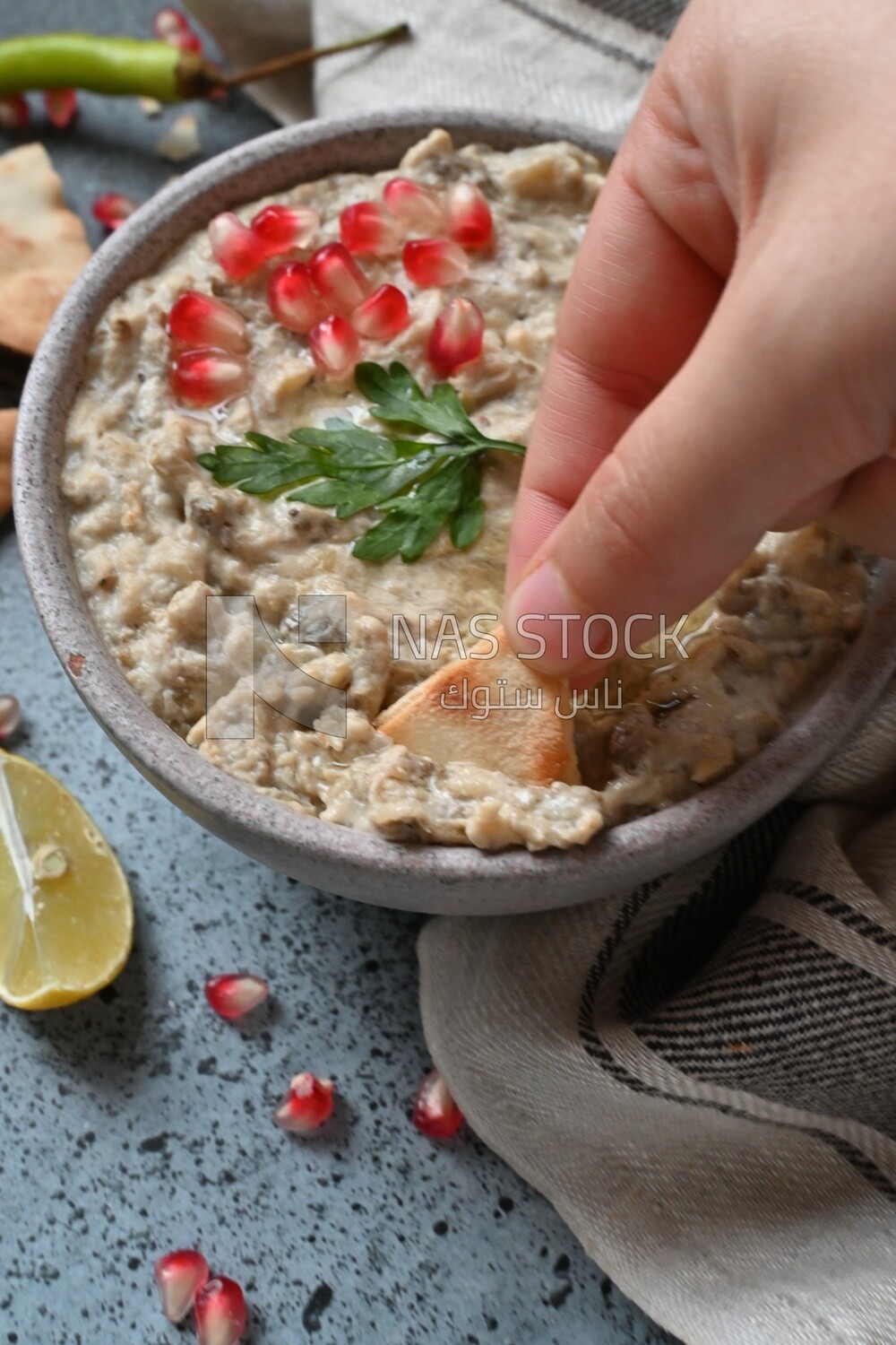 hand eating from a plate of lebanese baba ghanouj
