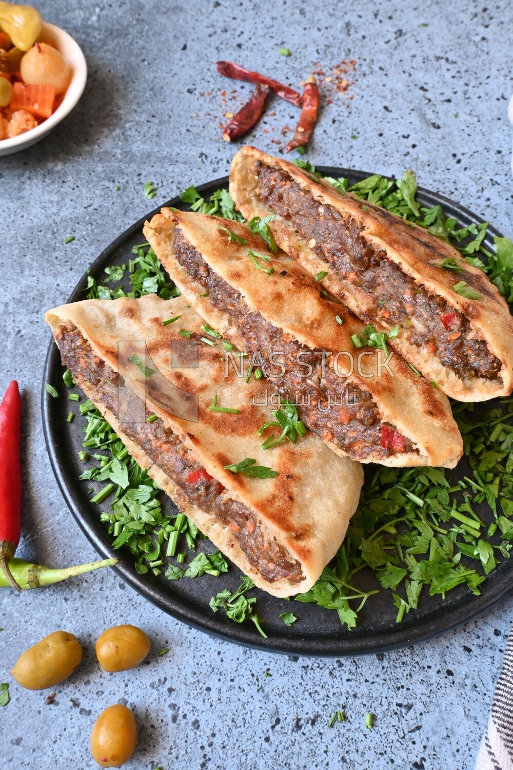 dish with hawawshi next to a spicy pepper