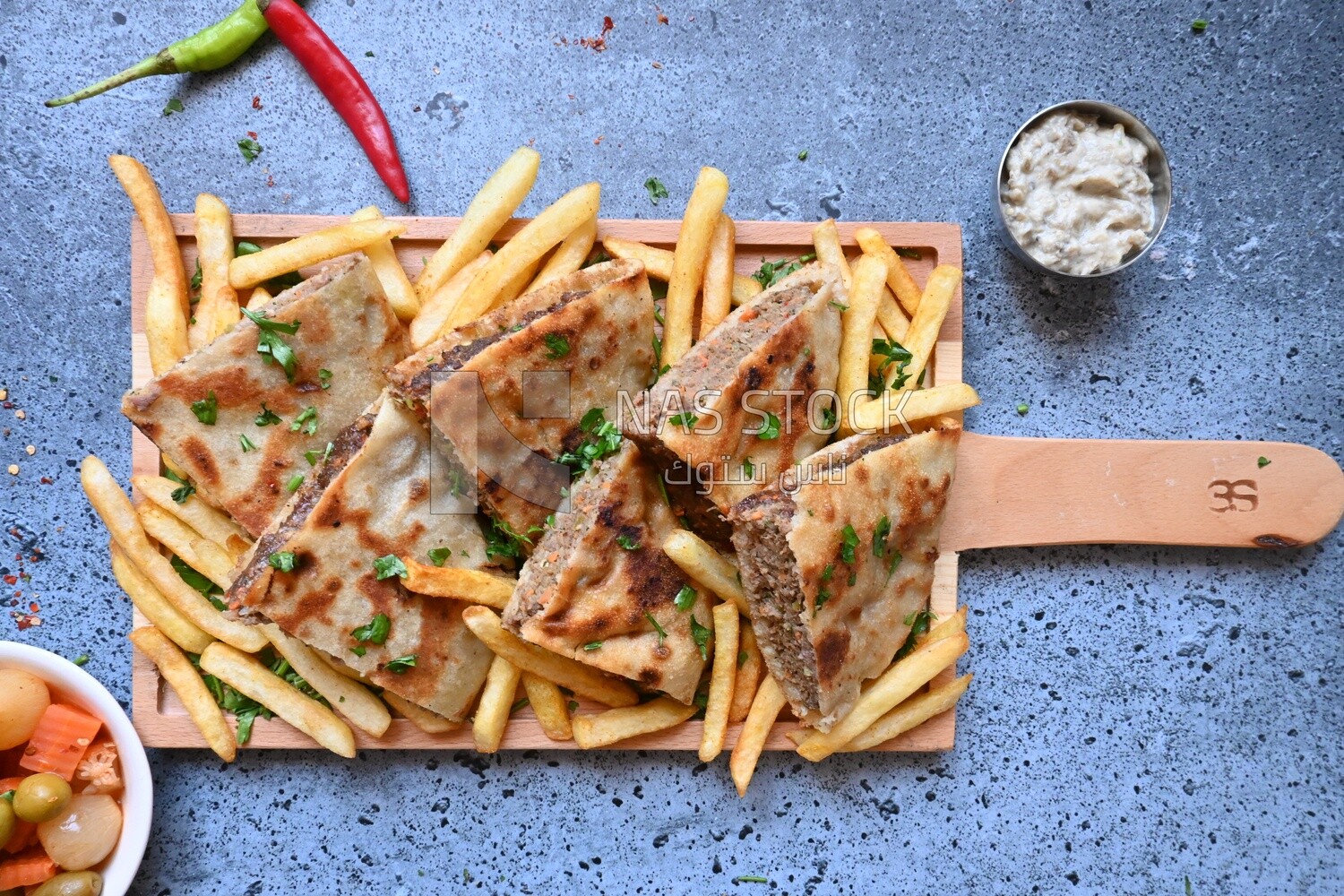 dish with hawawshi next to spicy pepper and fries