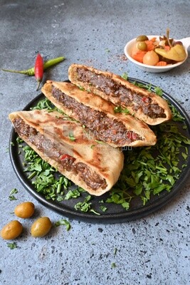 dish with hawawshi next to a spicy pepper