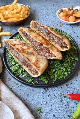 dish with hawawshi next to spicy pepper and fries