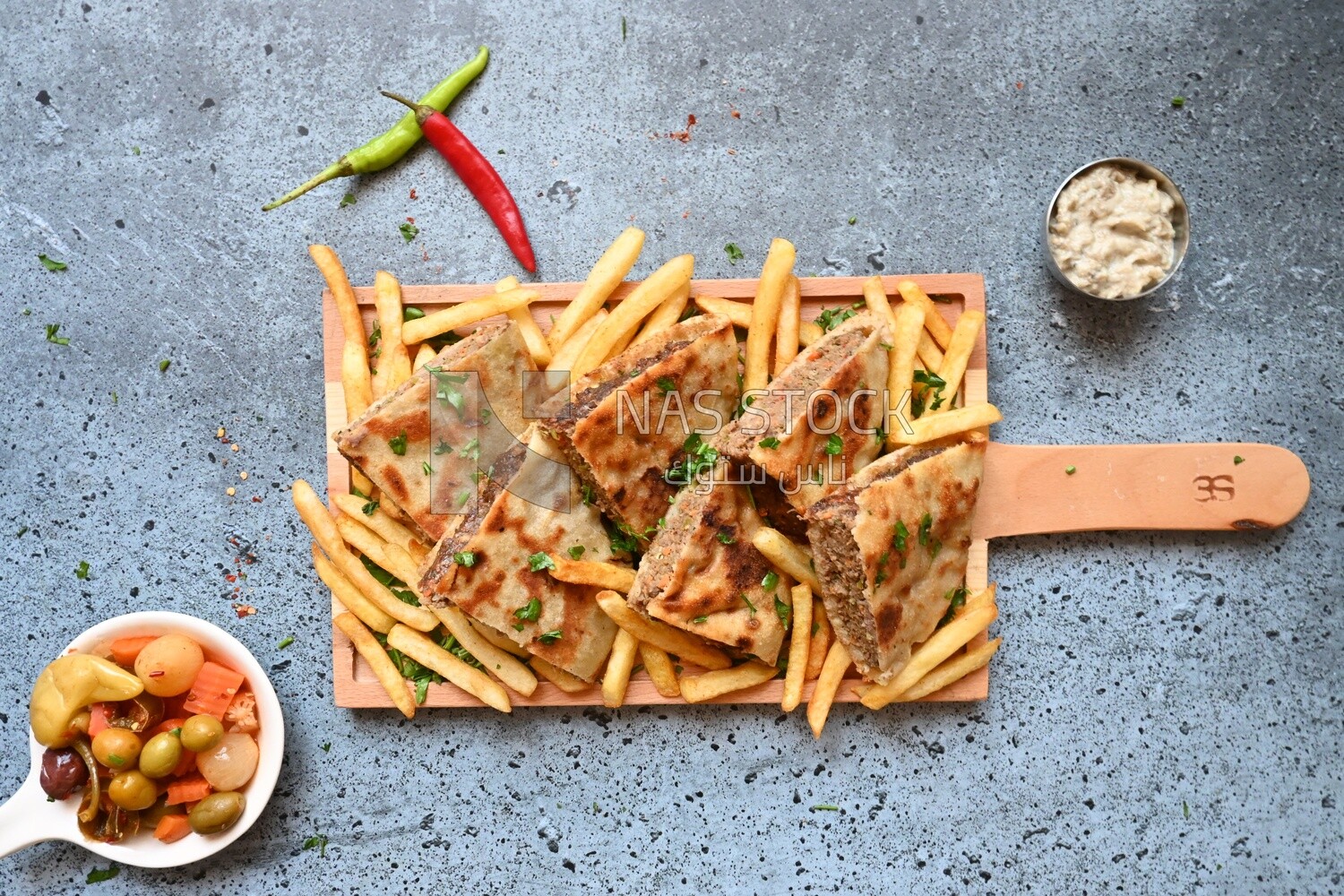 dish with hawawshi next to spicy pepper and fries