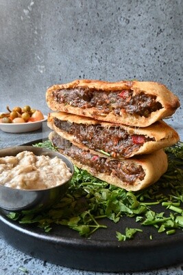dish with hawawshi on it with tahini sauce
