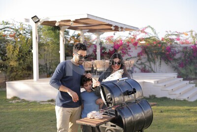 a couple preparing food on a barbecue grill