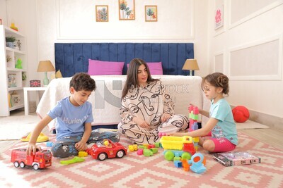 امراة تجلس مع اطفالها يلعبون 