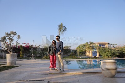 a husband with his wife standing in front of a swimming pool