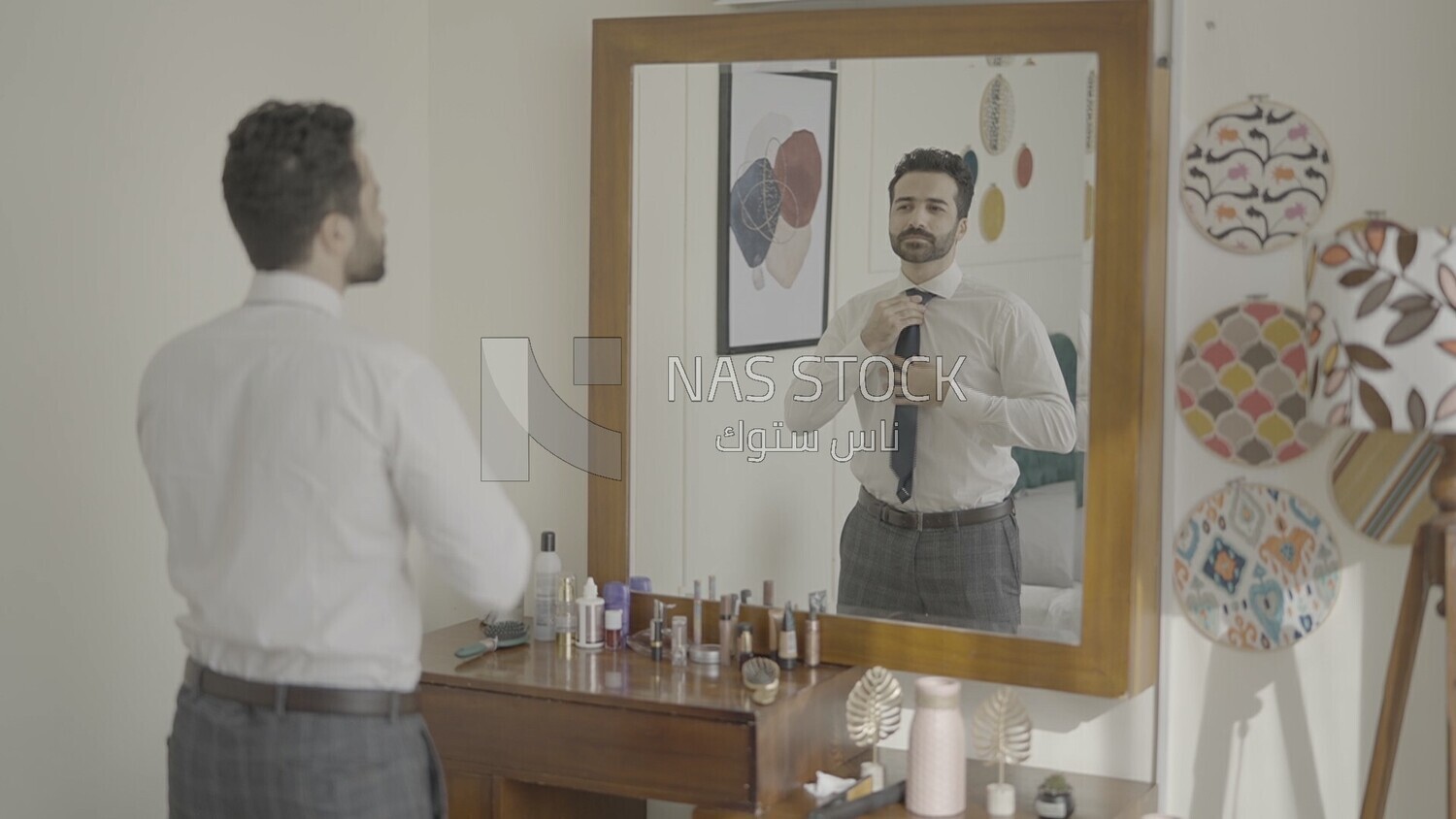 رجل يقف امام المرأة يرتدى سترة 