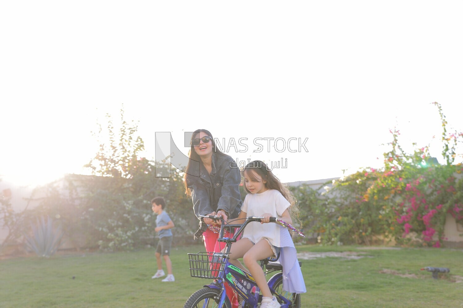 a woman helping her daughter ride a bike