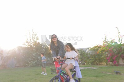 a woman helping her daughter ride a bike