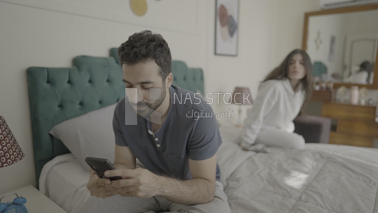 a man texting on the phone while her wife is beside him