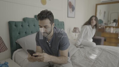 a man texting on the phone while her wife is beside him