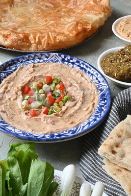 plate of foul with tahini and vegetables on it