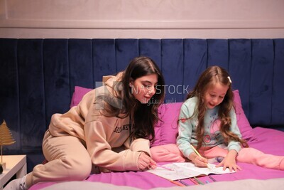 a mother with her daughter drawing together on the bed