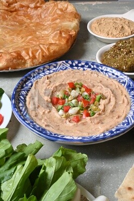 plate of foul with tahini and vegetables on it