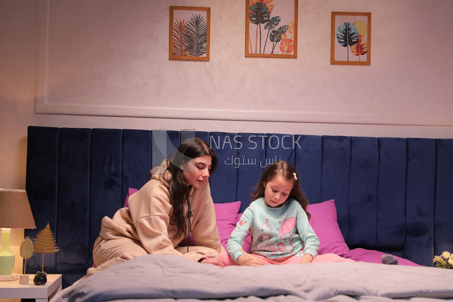 a mother with her daughter drawing together on the bed
