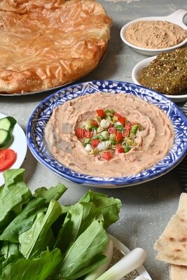 plate of foul with tahini and vegetables on it