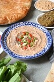 Plate of foul with tahini and vegetables on it