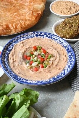 plate of foul with tahini and vegetables on it