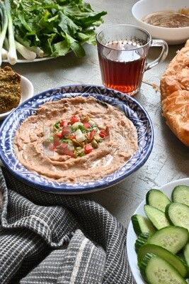 plate of foul with tahini and vegetables on it